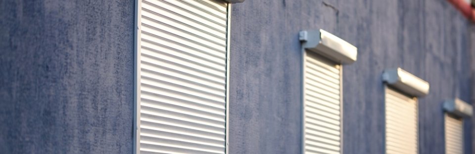 House facade with closed security rolling shutters on windows for protection and privacy