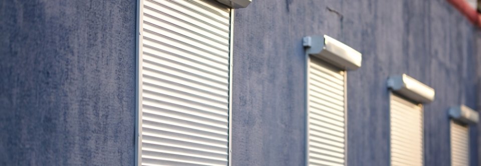 House facade with closed security rolling shutters on windows for protection and privacy