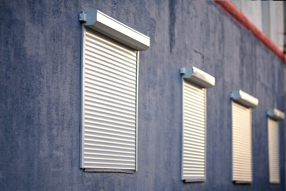House facade with closed security rolling shutters on windows for protection and privacy